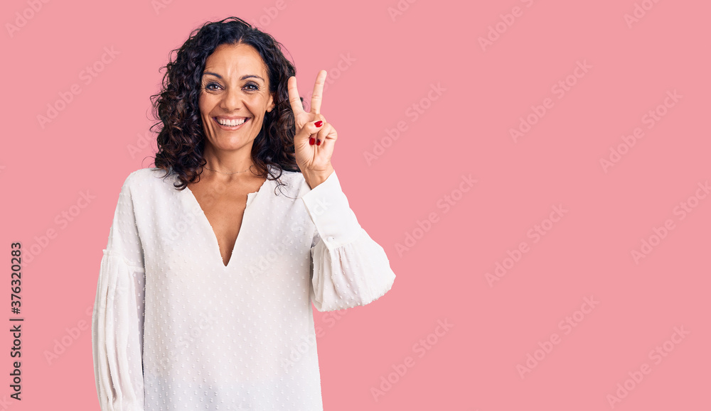 Middle age beautiful woman wearing casual sweater showing and pointing up with fingers number two while smiling confident and happy. Middle age beautiful woman wearing casual sweater showing and pointing up with fingers number two while smiling confident and happy.