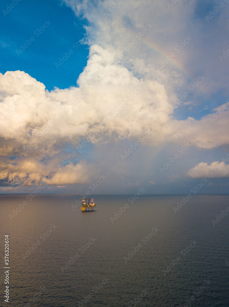 Aerial view from a drone of an offshore jack up rig at the offshore location during raining time with rainbow