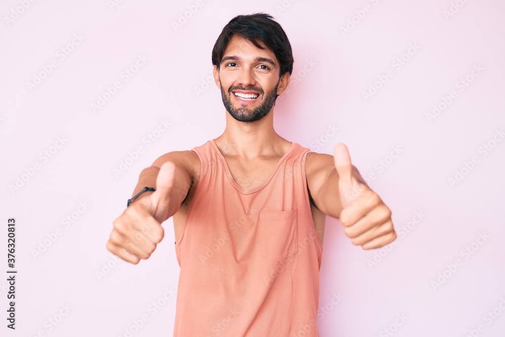 Fototapeta premium Handsome hispanic man wearing casual clothes approving doing positive gesture with hand, thumbs up smiling and happy for success. winner gesture.