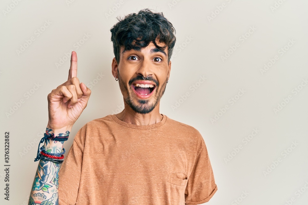 Young hispanic man wearing casual clothes pointing finger up with successful idea. exited and happy. number one. Young hispanic man wearing casual clothes pointing finger up with successful idea. exited and happy. number one.