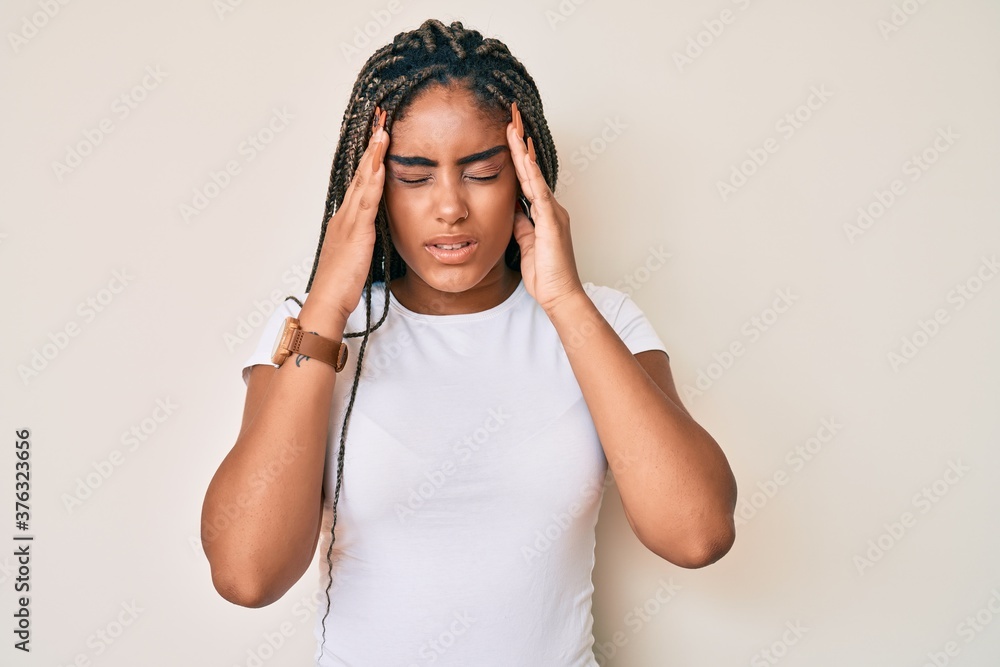Young african american woman with braids wearing casual white tshirt with hand on head for pain in head because stress. suffering migraine. Young african american woman with braids wearing casual white tshirt with hand on head for pain in head because stress. suffering migraine.