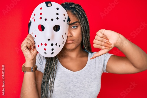 Canvas Print Young african american woman with braids wearing hockey mask with angry face, ne