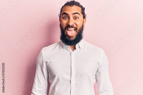 Young arab man wearing casual clothes sticking tongue out happy with funny expression. emotion concept.