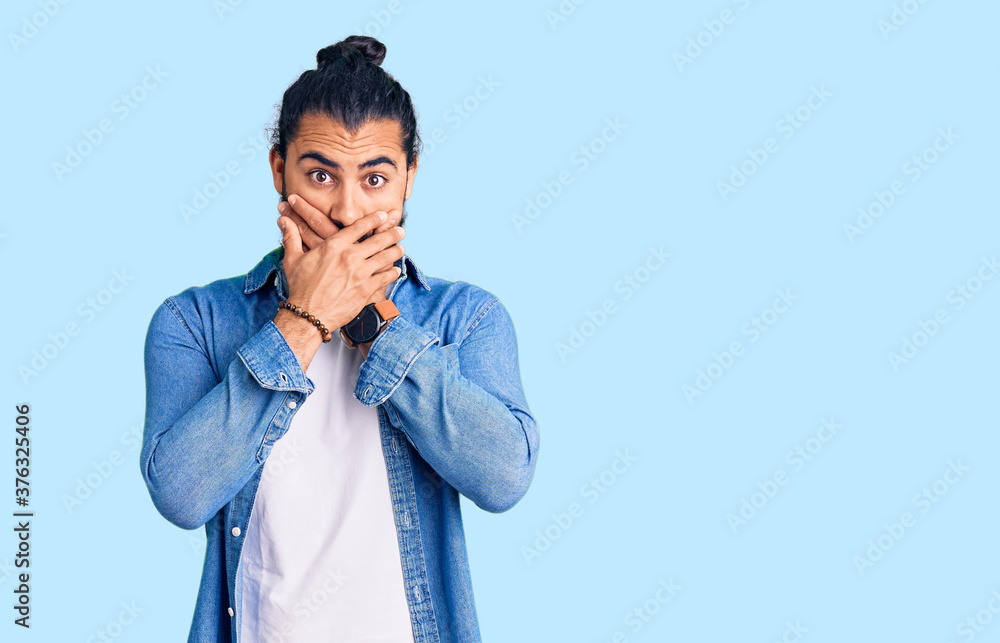 Young arab man wearing casual denim shirt shocked covering mouth with hands for mistake. secret concept. Young arab man wearing casual denim shirt shocked covering mouth with hands for mistake. secret concept.