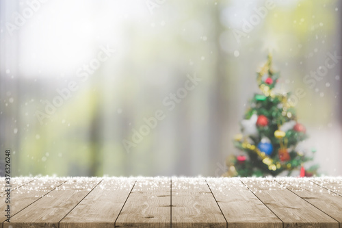 Empty wood table top on blur with bokeh Christmas tree and new's year decoration on window banner background with snowfall - can be used for display or montage your products.