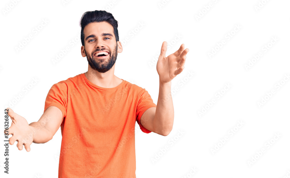 Fototapeta premium Young handsome man with beard wearing casual t-shirt smiling cheerful offering hands giving assistance and acceptance.