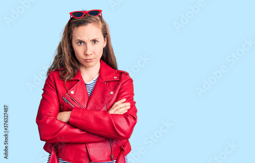 Young beautiful blonde woman wearing casual leather jacket skeptic and nervous, disapproving expression on face with crossed arms. negative person.