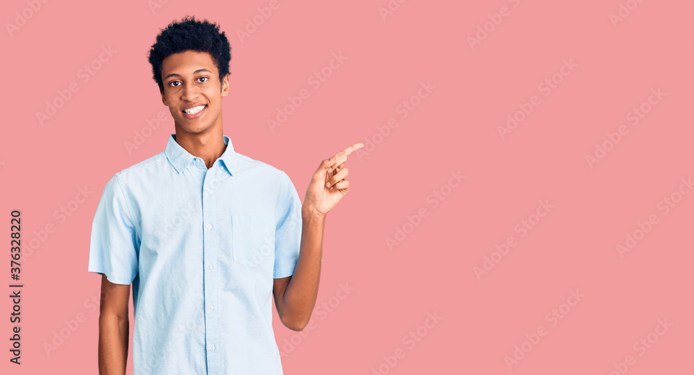 Young african american man wearing casual clothes with a big smile on face, pointing with hand finger to the side looking at the camera. Young african american man wearing casual clothes with a big smile on face, pointing with hand finger to the side looking at the camera.