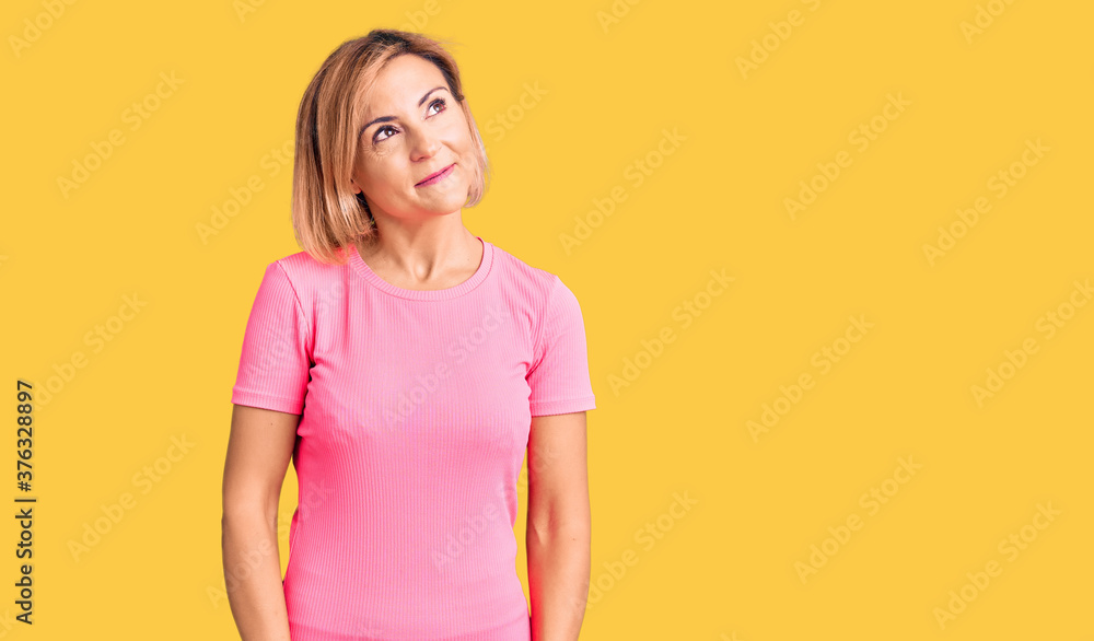 Young blonde woman wearing sportswear smiling looking to the side and staring away thinking. Young blonde woman wearing sportswear smiling looking to the side and staring away thinking.