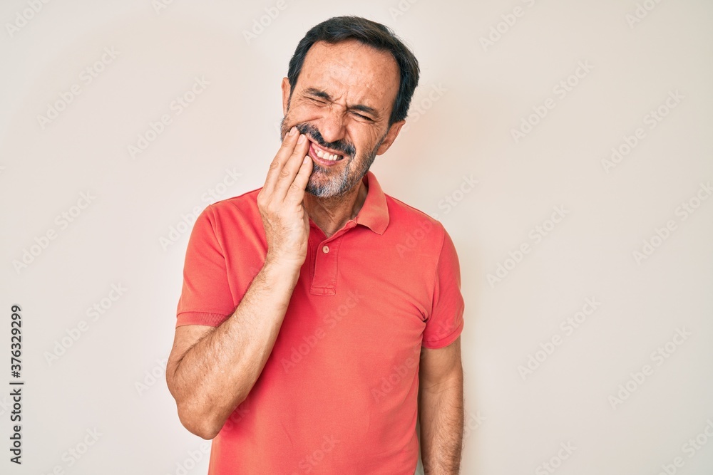 Middle age hispanic man wearing casual clothes touching mouth with hand with painful expression because of toothache or dental illness on teeth. dentist
