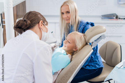 A female pediatric dental specialist going over the results of the girl s oral checkup with her mom. Dentist office.