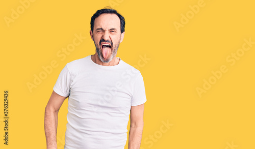 Middle age handsome man wearing casual t-shirt sticking tongue out happy with funny expression. emotion concept.