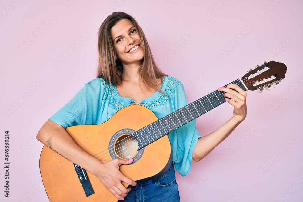 Beautiful caucasian woman playing classical guitar smiling with a happy and cool smile on face. showing teeth. Beautiful caucasian woman playing classical guitar smiling with a happy and cool smile on face. showing teeth.