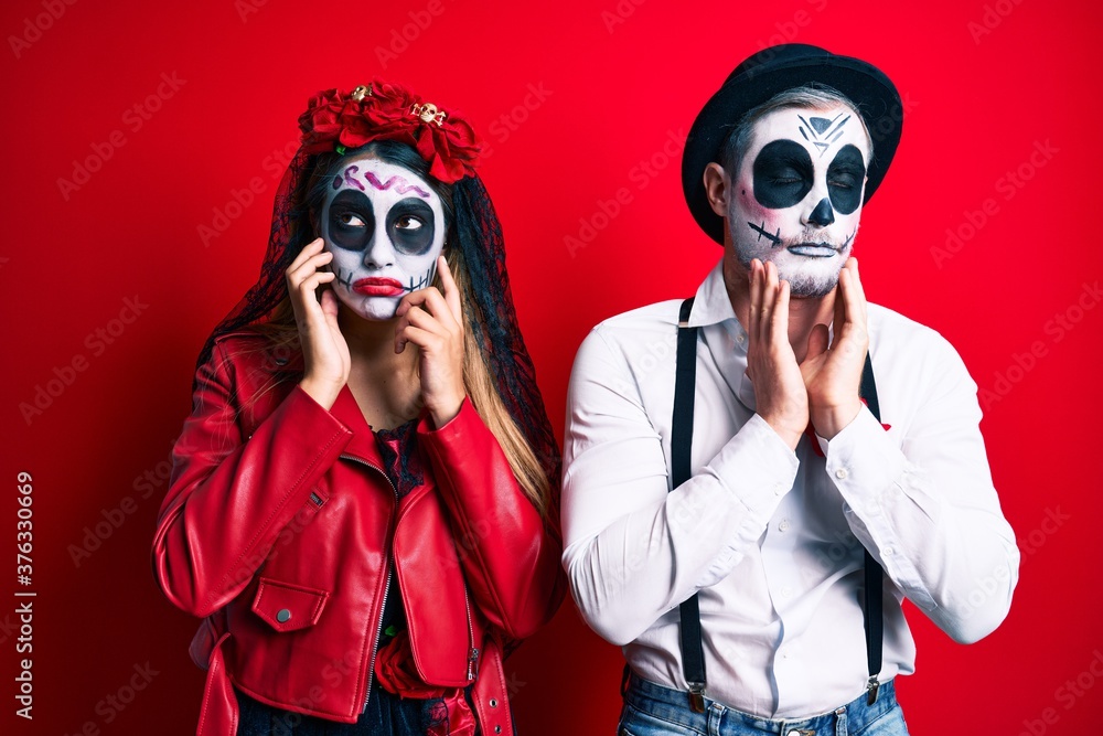 Couple wearing day of the dead costume over red tired hands covering face, depression and sadness, upset and irritated for problem Couple wearing day of the dead costume over red tired hands covering face, depression and sadness, upset and irritated for problem