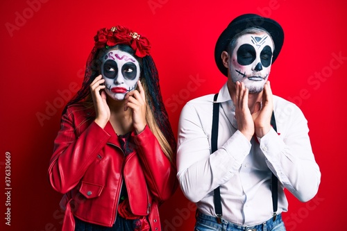 Couple wearing day of the dead costume over red tired hands covering face  depression and sadness  upset and irritated for problem