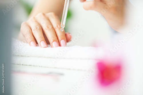 Moisturizing oil for cuticles  woman cares for hands and nails.