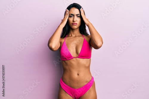 Beautiful hispanic woman wearing bikini suffering from headache desperate and stressed because pain and migraine. hands on head. © Krakenimages.com