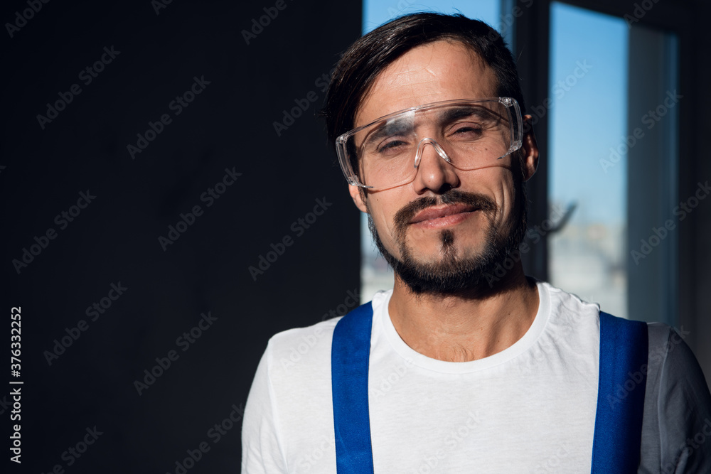 Obraz premium Male engineer wearing blue overalls and goggles on his head