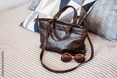Woman brown leather bag on the gray sofa, female accessory.