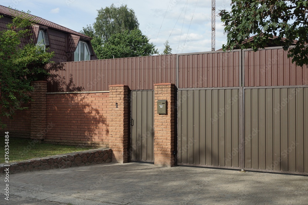 one brown gate and part of the fence of bricks and metal in the wall on a city street