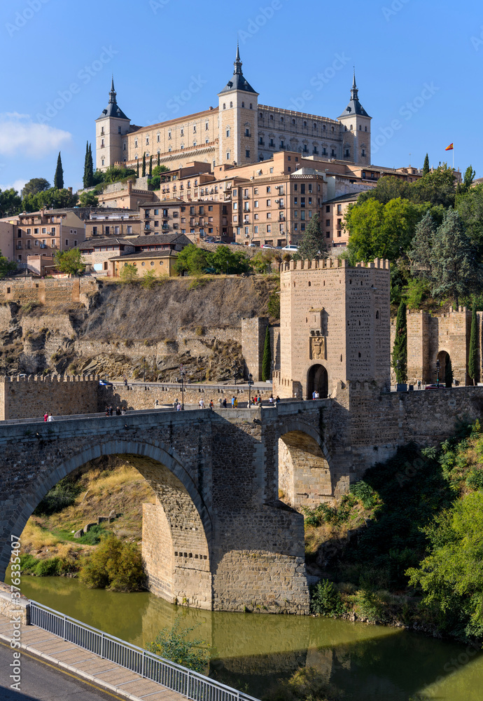 Toledo Spain - Morning view of historic city Toledo at Puente de Alcántara, a Roman arch bridge at front of east city gate Puerta de Alcántara and crossing over Tagus River. Toledo, Spain.