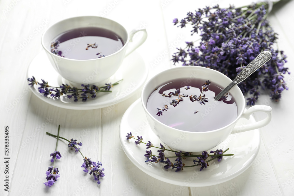 Fresh delicious tea with lavender and beautiful flowers on white wooden table Fresh delicious tea with lavender and beautiful flowers on white wooden table