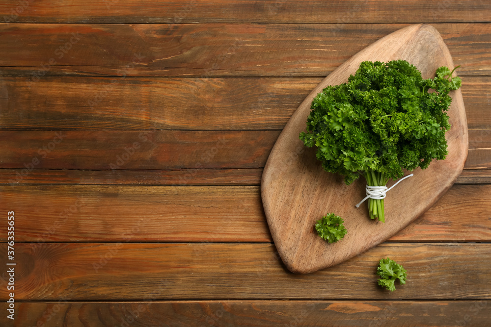 Bunch of fresh curly parsley on wooden table, flat lay. Space for text Bunch of fresh curly parsley on wooden table, flat lay. Space for text