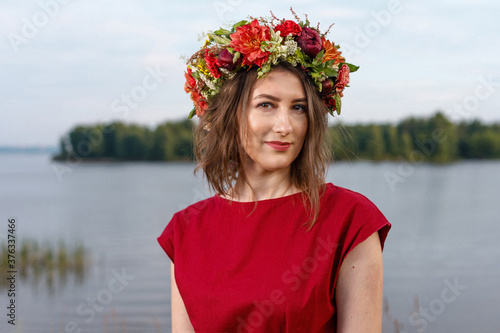 Slavic beauty with a flower wreath on her head in the lap of nature. Ancient pagan origin celebration concept. Summer solstice day. Mid summer. Ancient rituals. photo