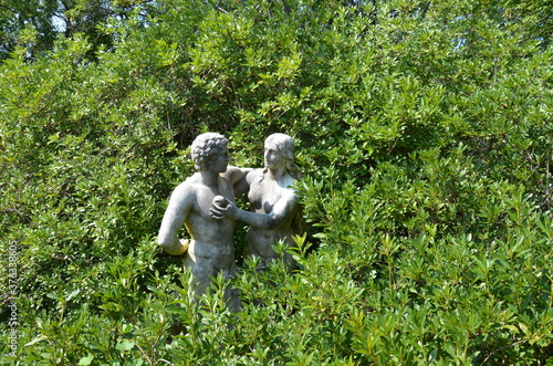Adam and Eve statue with apple and green plants
