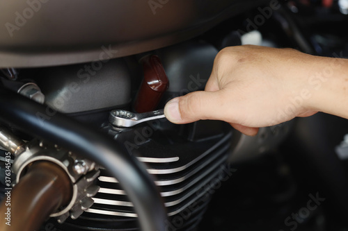 Mechanic using a wrench and socket on cylinder head of a motorcycle .maintenance,repair motorcycle concept in garage .selective focus