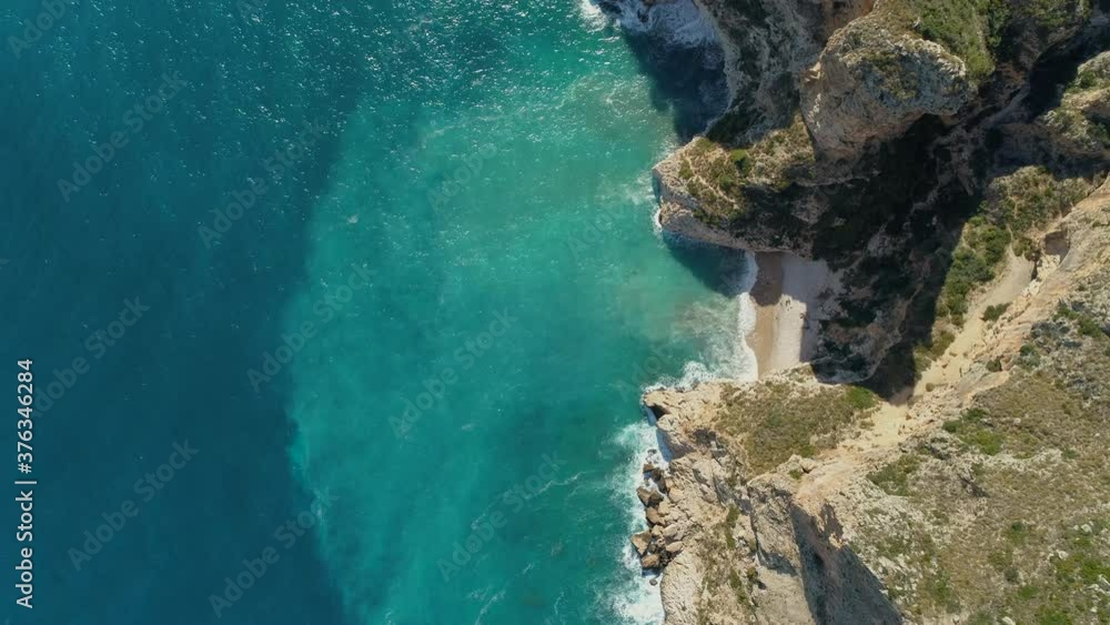 Aerial top down view of a beautiful beach with turquoise waters between the cliffs in the mediterranean coast of Spain. Aerial top down view of a beautiful beach with turquoise waters between the cliffs in the mediterranean coast of Spain.