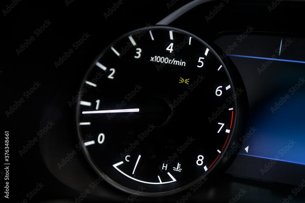 dashboard of the car is illuminated by bright  circle tachometer.
