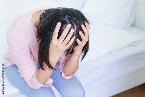 Upset depressed young woman sitting on bed feeling strong headache migraine, sad tired drowsy teenager exhausted girl resting trying to sleep after nervous tension and stress, somnolence concept