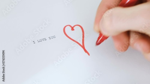 drawing a heart shape with a red marker pen on a pager sheet where typed I love you photo