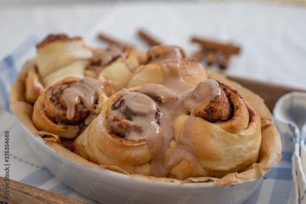 Cinnamon rolls with sugar frosting. With cinnamon sticks and spices, wooden background Cinnamon rolls with sugar frosting. With cinnamon sticks and spices, wooden background