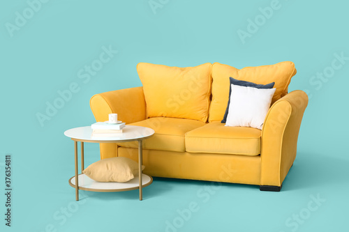 Stylish sofa and table on color background