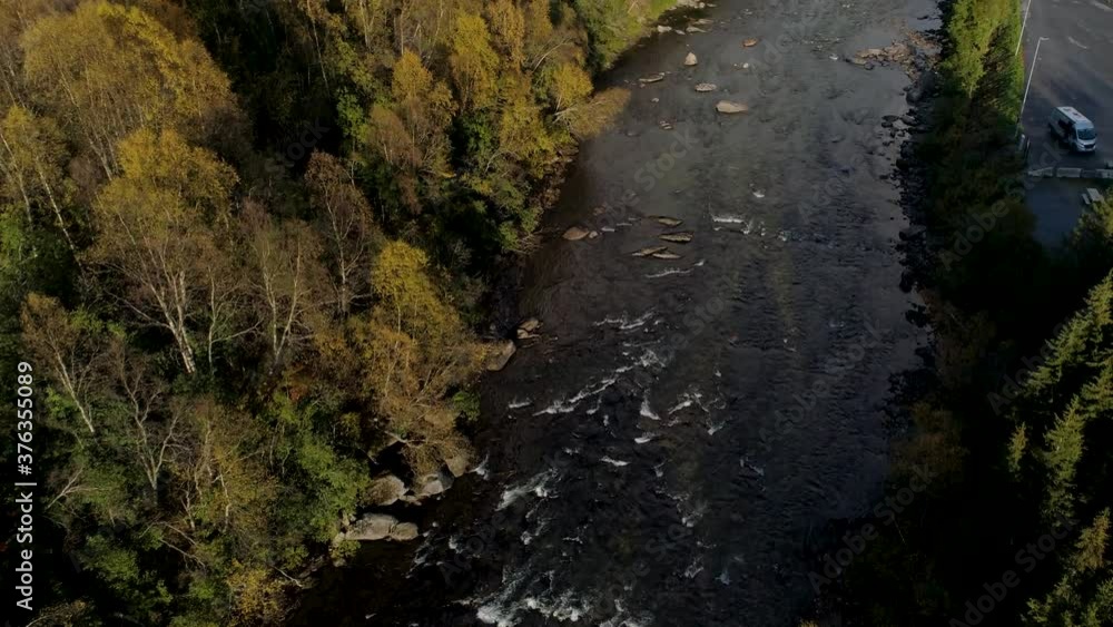 Aerial view over rapids revealing Norwegian mountains and fall foliage forest, sunny autumn day, in Troms, Nordland, Norway - Tilt up, drone shot Aerial view over rapids revealing Norwegian mountains and fall foliage forest, sunny autumn day, in Troms, Nordland, Norway - Tilt up, drone shot