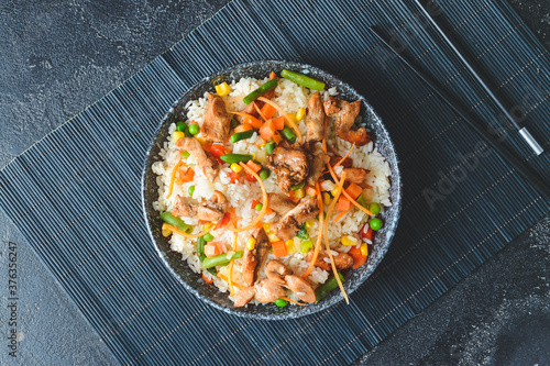 Bowl with tasty fried rice on dark background