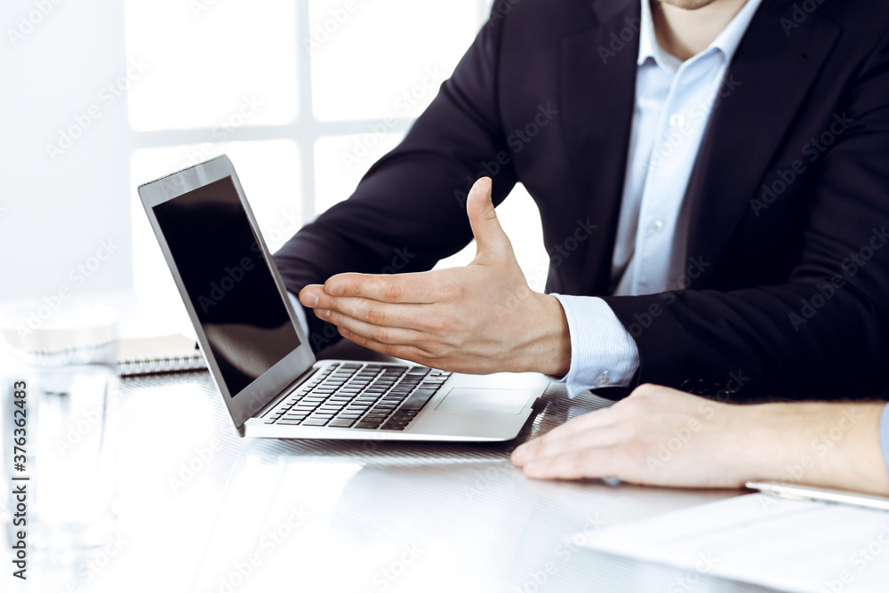 Business people using laptop computer while working together at the desk in modern office. Unknown businessman or male entrepreneur with colleague at workplace. Teamwork and partnership concept Business people using laptop computer while working together at the desk in modern office. Unknown businessman or male entrepreneur with colleague at workplace. Teamwork and partnership concept