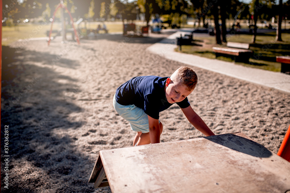 Young boy playing in public park during summer day Young boy playing in public park during summer day