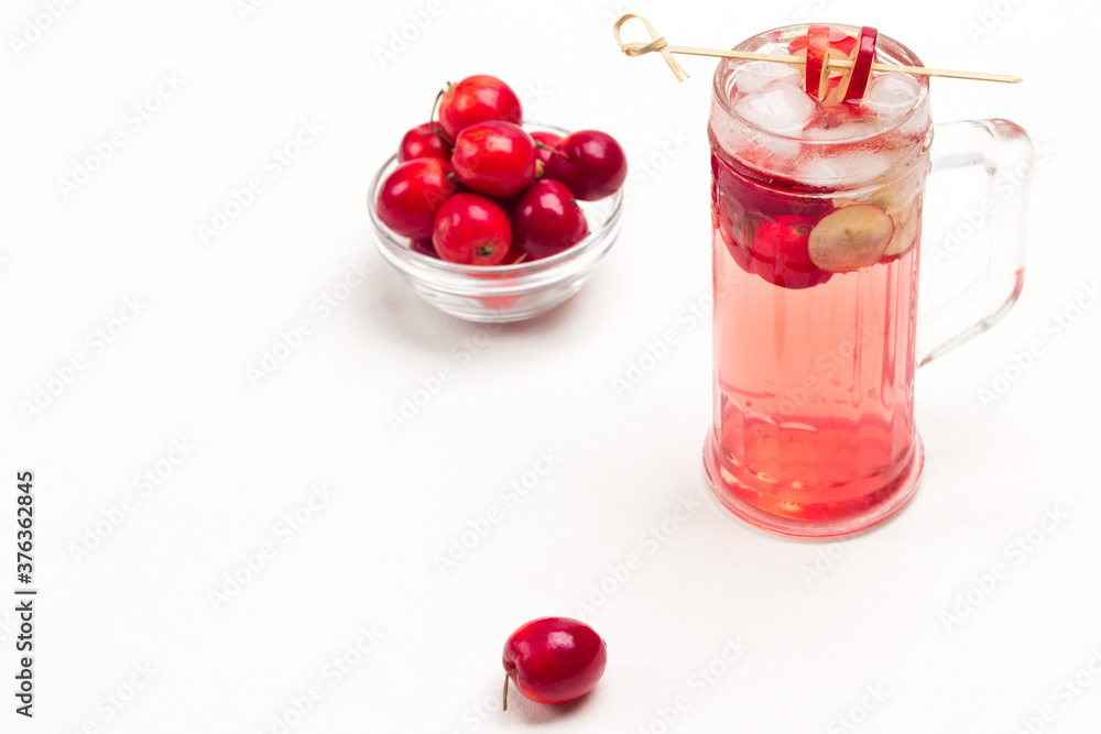Homemade refreshing summer apple drink with ice in glass. Sliced apples on stick. Small red apples in glass cup Homemade refreshing summer apple drink with ice in glass. Sliced apples on stick. Small red apples in glass cup