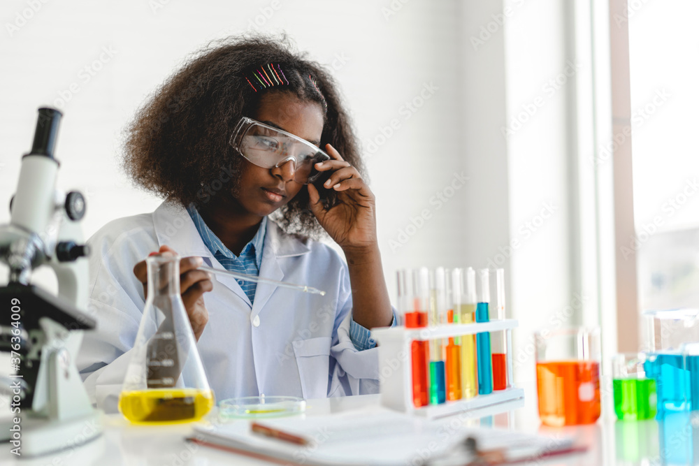 African american cute little girl student child learning research and doing a chemical experiment while making analyzing and mixing liquid in glass at science class on the table.Education African american cute little girl student child learning research and doing a chemical experiment while making analyzing and mixing liquid in glass at science class on the table.Education