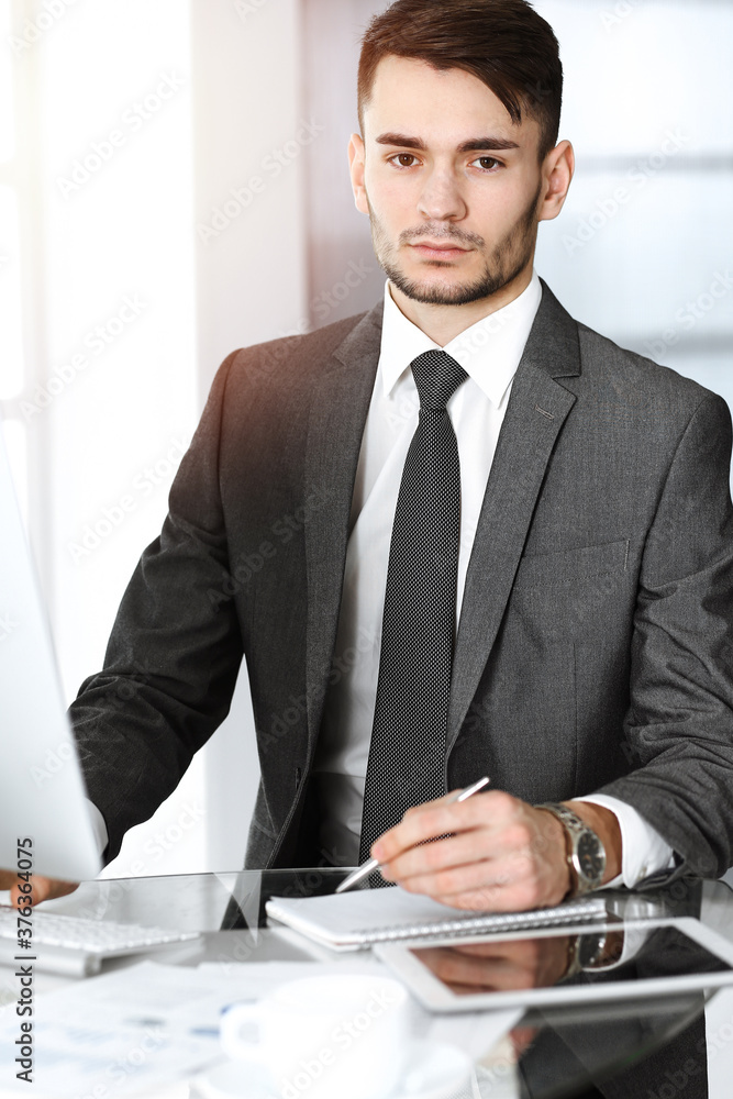 Businessman working with computer in sunny office. Headshot of male entrepreneur at workplace. Business concept Businessman working with computer in sunny office. Headshot of male entrepreneur at workplace. Business concept