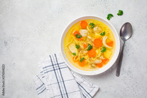 Obraz na plátně Homemade chicken soup with noodles and vegetables in white bowl, white background, top view