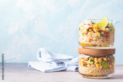Fényképezés Vegan salad with vegetables and quinoa in glass jars, blue background