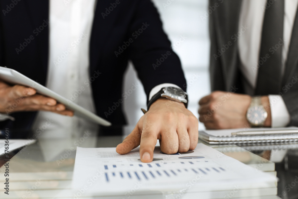 Business people using tablet computer while working together in modern office. Unknown businessman sitting at the desk with his colleague or partner. Teamwork and partnership concept Business people using tablet computer while working together in modern office. Unknown businessman sitting at the desk with his colleague or partner. Teamwork and partnership concept