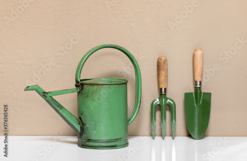 Set of small green garden tools against a wall