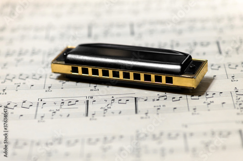Tableau sur toile Mouth organ or harmonica on a music score