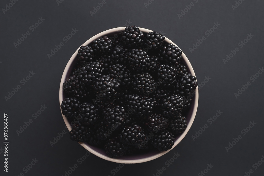 Fresh blackberries in a bowl against a dark background. Fresh blackberries in a bowl against a dark background.