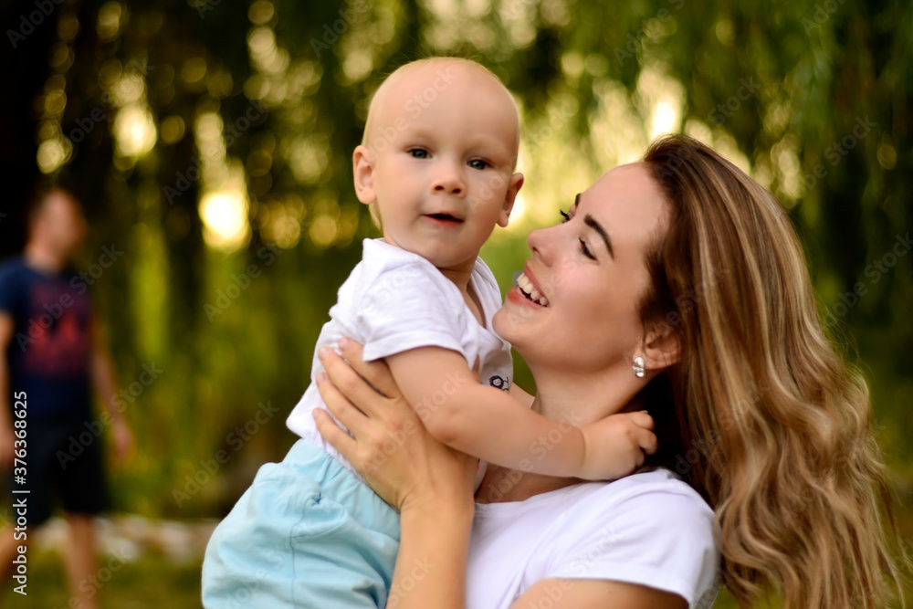 A young mother holds her young son in her arms in a Park
